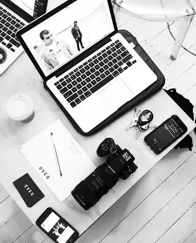 Best web developer in Bahrain working with a laptop, professional camera, smartphone, notebook, and creative workspace.